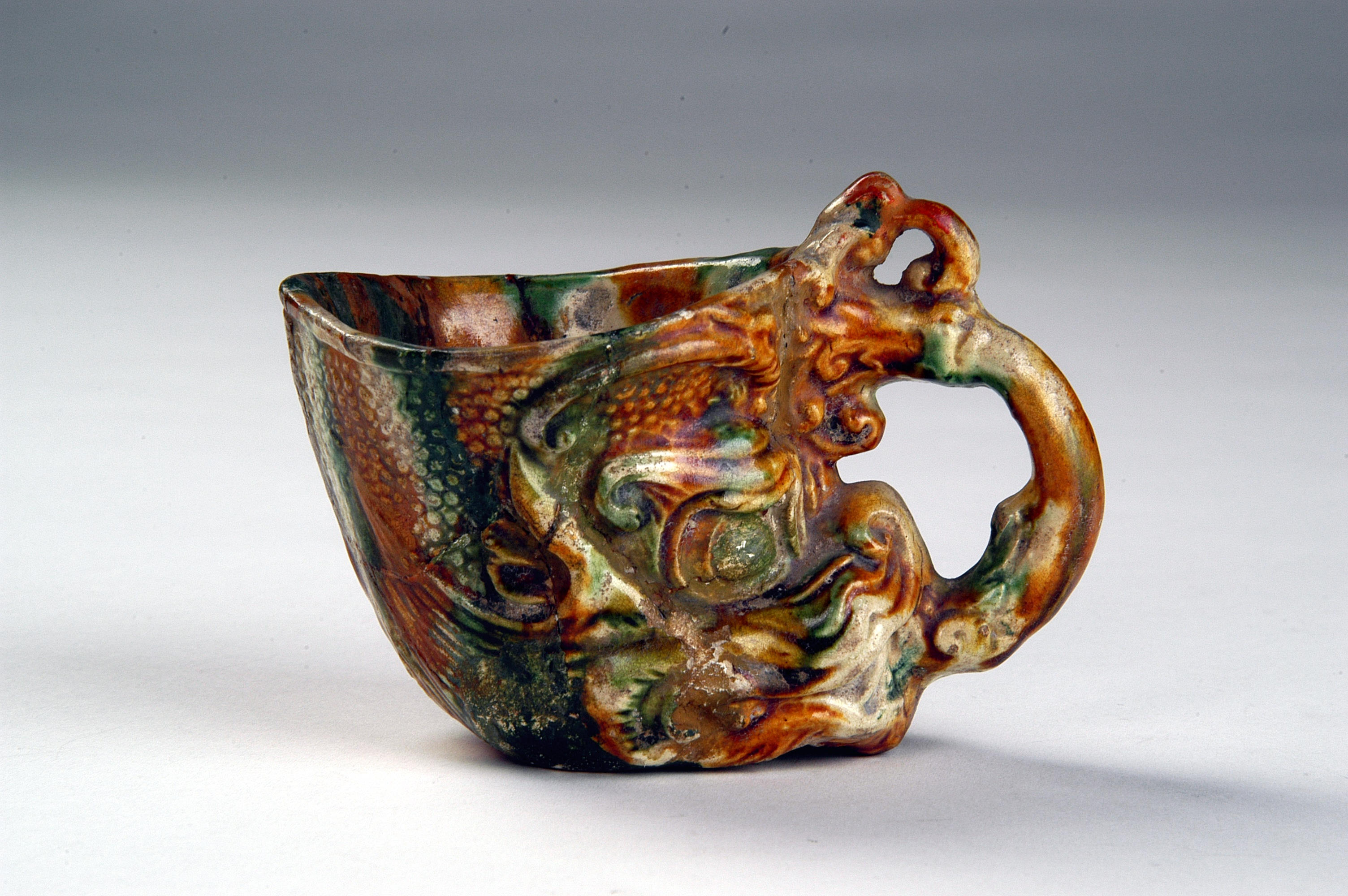 呈龍首狀，上飾鱗紋的三彩龍首杯，於河南洛陽出土。（洛陽博物館藏）