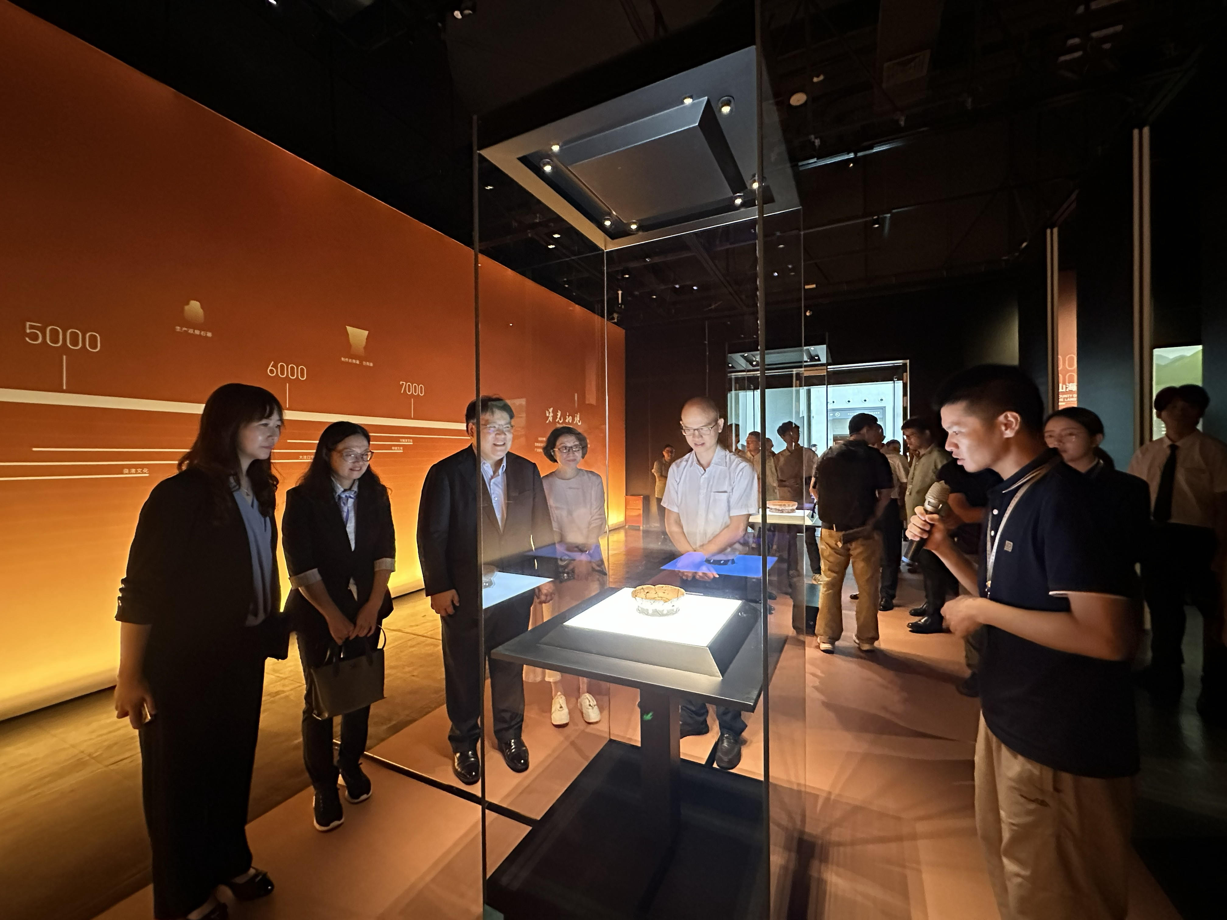 主禮嘉賓參觀展覽，我與澳門博物館館長盧可茵（左一）、廣東省文化和旅遊廳二級巡視員東田（左二）、廣東省文物考古研究院院長曹勁（左四）、中山市博物館館長余子龍（右二）一同聆聽策展人陳慶海（右一）介紹由古蹟辦借出的鏤孔圈足陶盤。