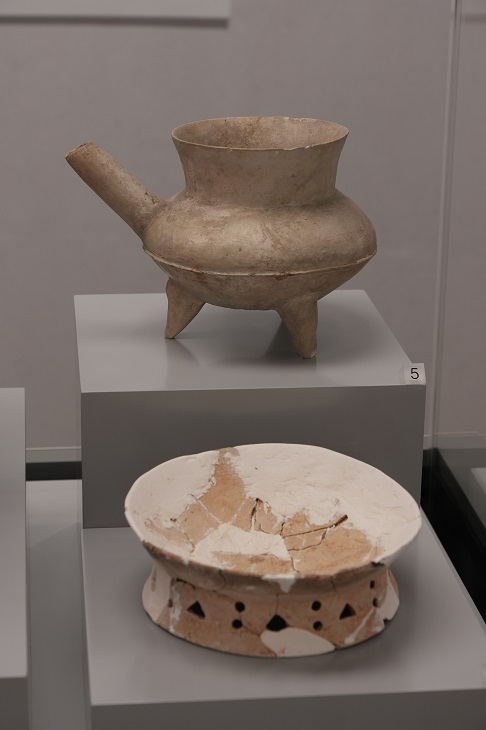 山東的白陶三足盉（上），是酒水類盛器，酒水入口與出口徹底分開，方便實用（山東博物館藏）；白陶鏤孔圈足盤（下）於長洲東灣出土，估計用來盛載美食，祭祀神靈（古物古蹟辦事處藏）。