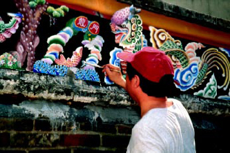 Artist repainting the moulded panel of King Law Ka Shuk.